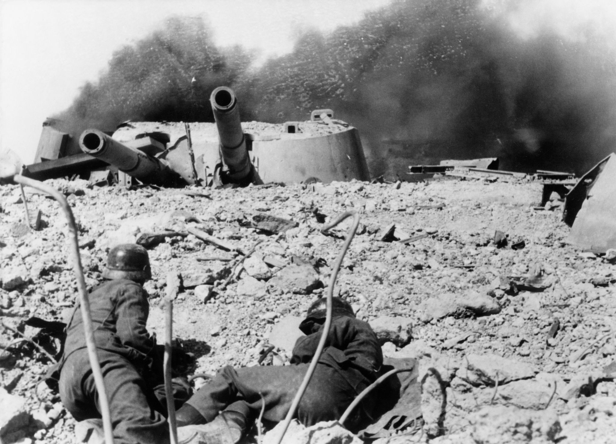 Немецкие солдаты в бою в районе 30-й батареи Севастополя. В кадре горящая башенная артиллерийская установка МБ-2-12 №2. Немцам так и не удалось подавить наши батареи ни артиллерийским огнем, ни с помощью авиации. 1 июля 1942 года 35-я батарея выпустила последние 6 снарядов прямой наводкой по наступающей пехоте противника, и в ночь на 2 июля командир батареи капитан Лещенко организовал подрыв батаре